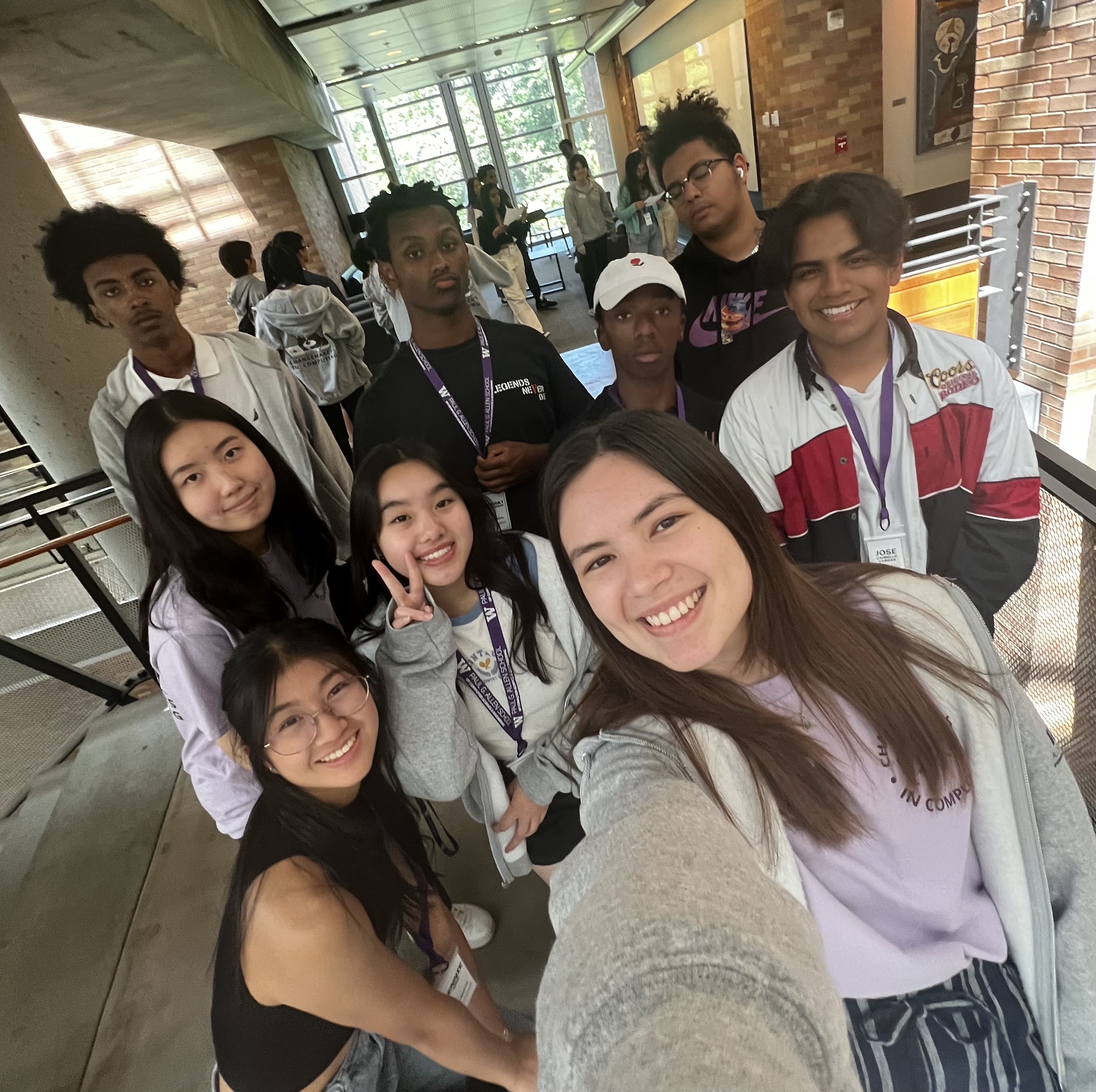 A group of 9 students smiling at a camera for a selfie