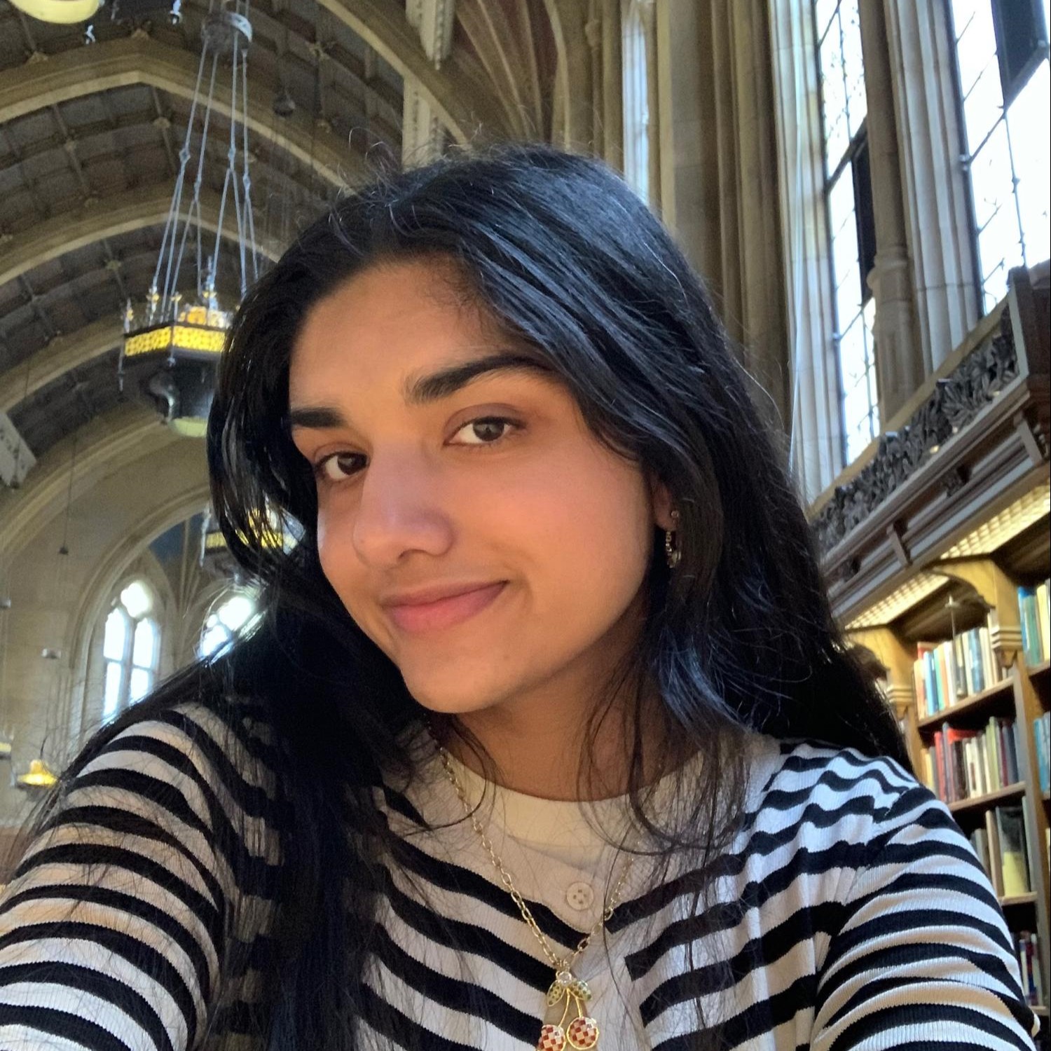 Image of a young Indian-American girl in a striped sweater studying in Suzzallo library.